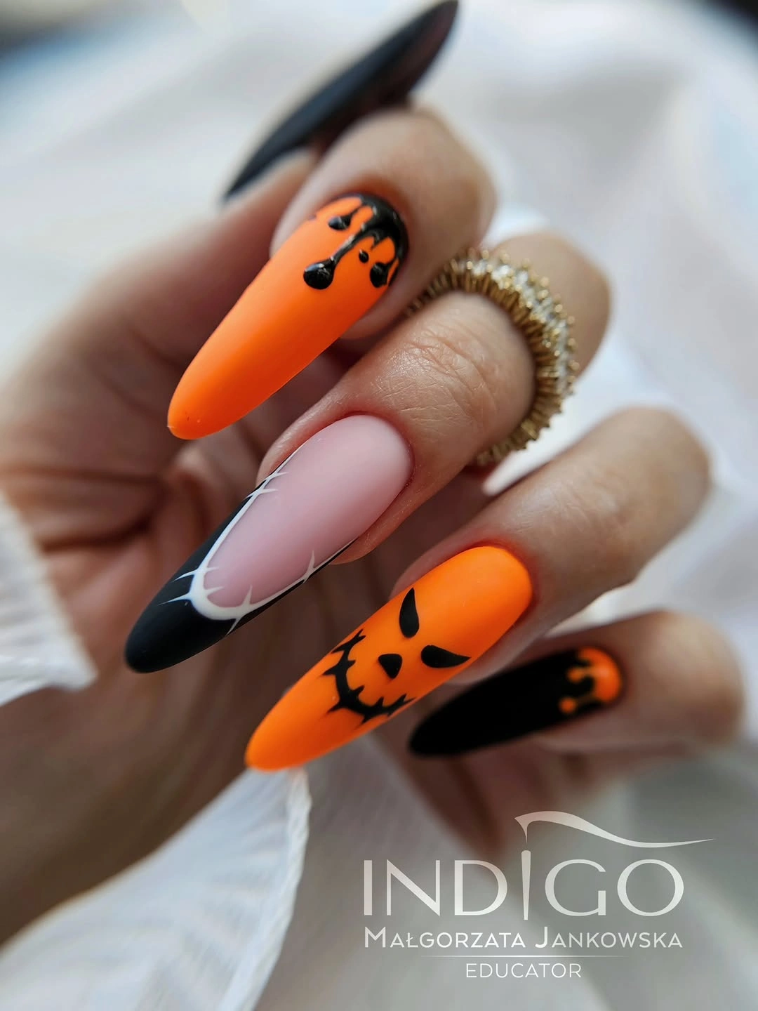 Neon orange stiletto nails with pumpkin faces and black tips