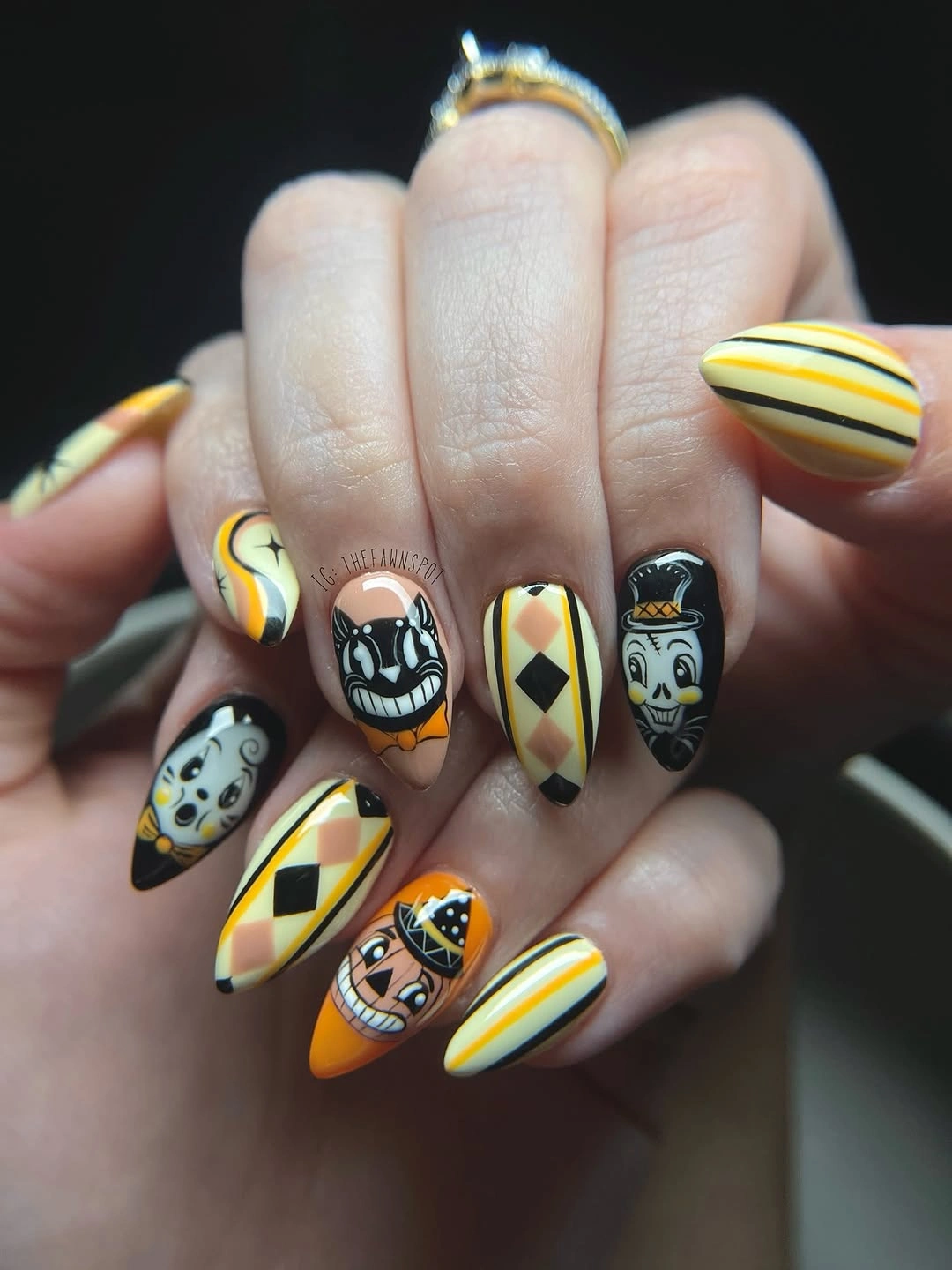Yellow almond nails with stripes, diamonds, and spooky faces