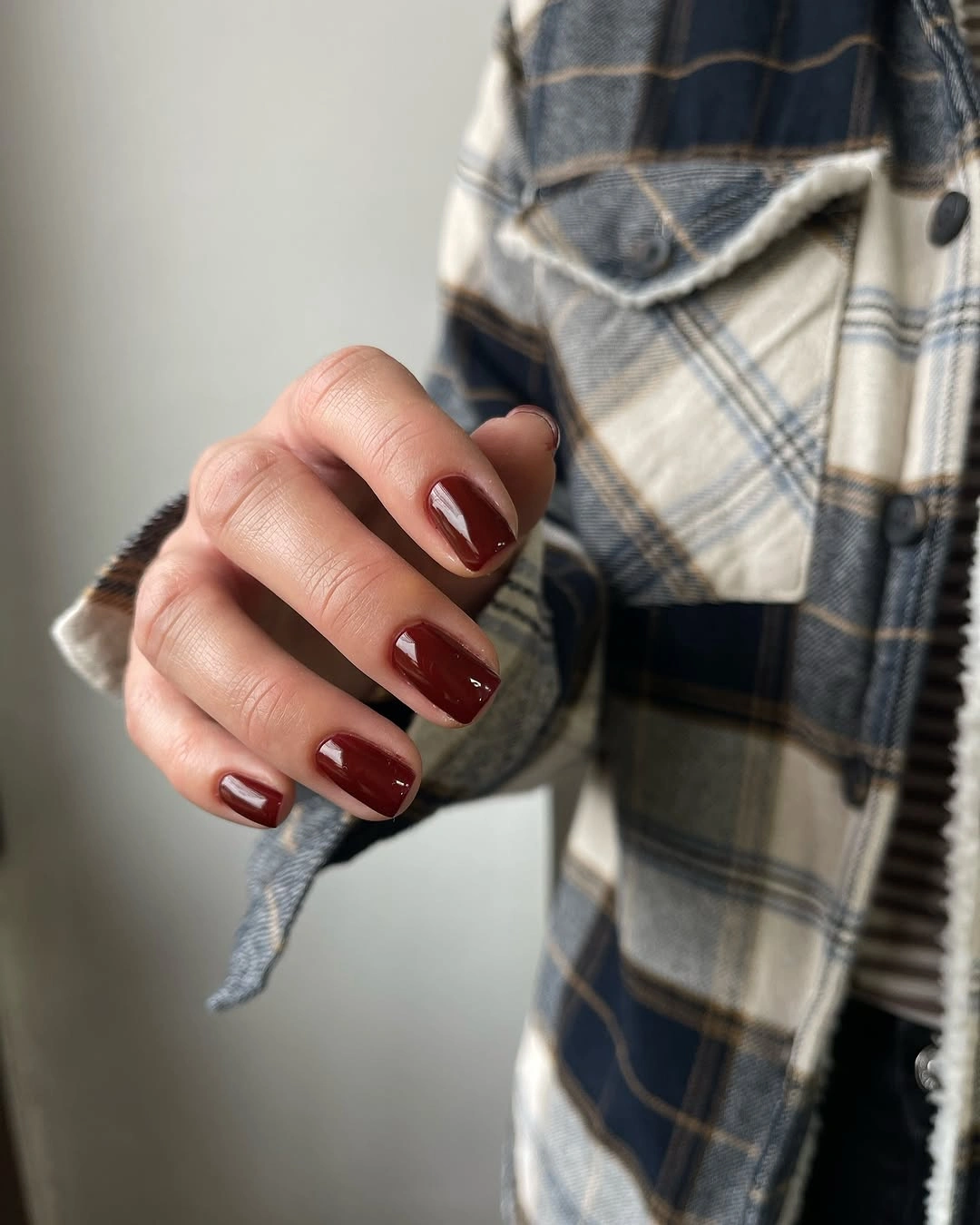short rounded square nails painted in a deep glossy oxblood burgundy