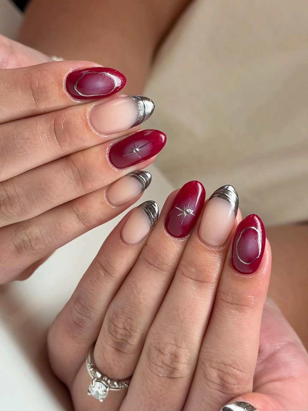 medium nude nails with maroon oval panels silver-toned tip edges and small star detail