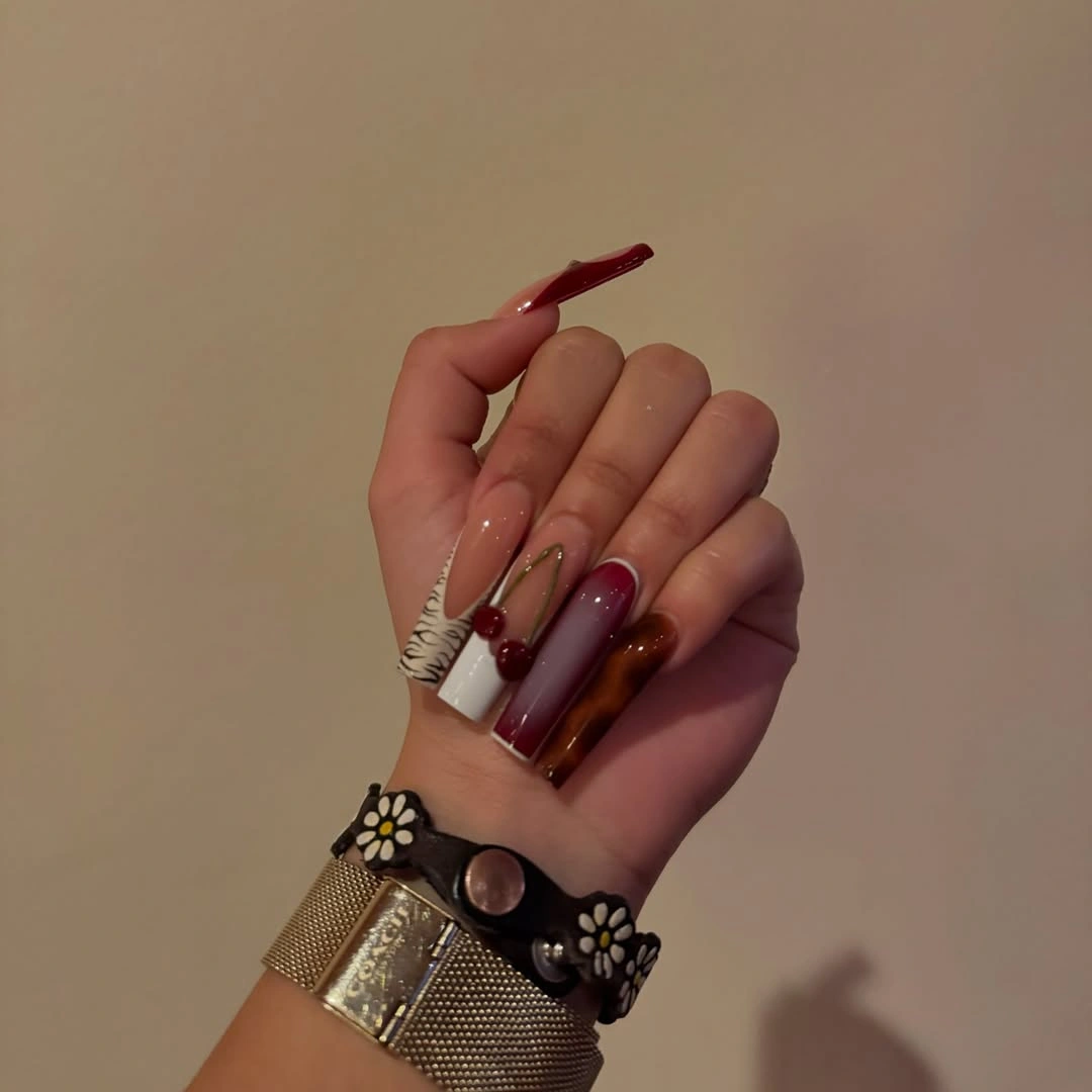 long dark red nails with small warm amber and yellow accent areas