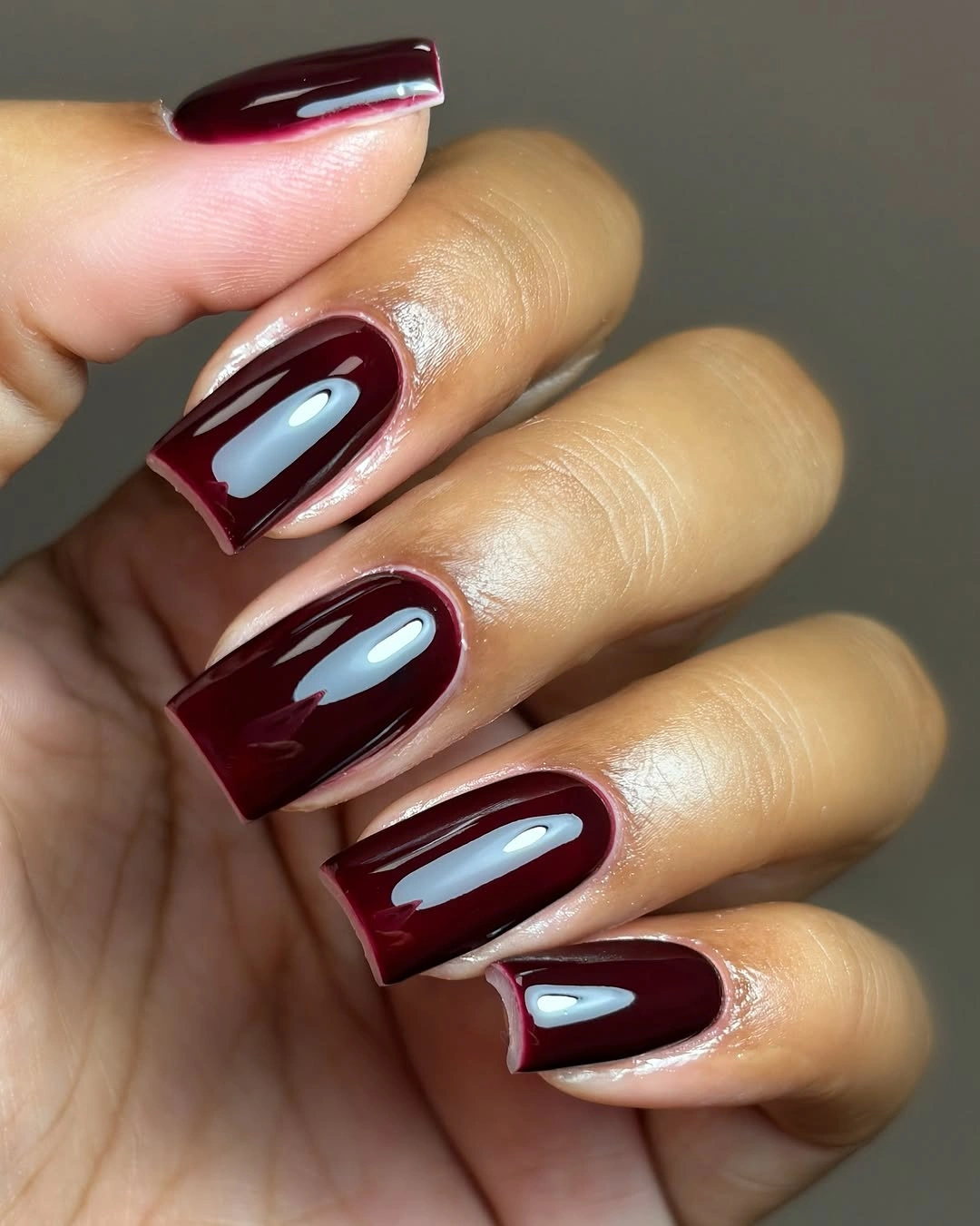 medium square burgundy nails with a slim pale curved French-style edge