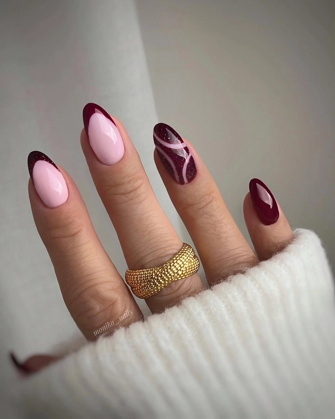 pale pink almond nails with maroon French tips and diagonal curved accent