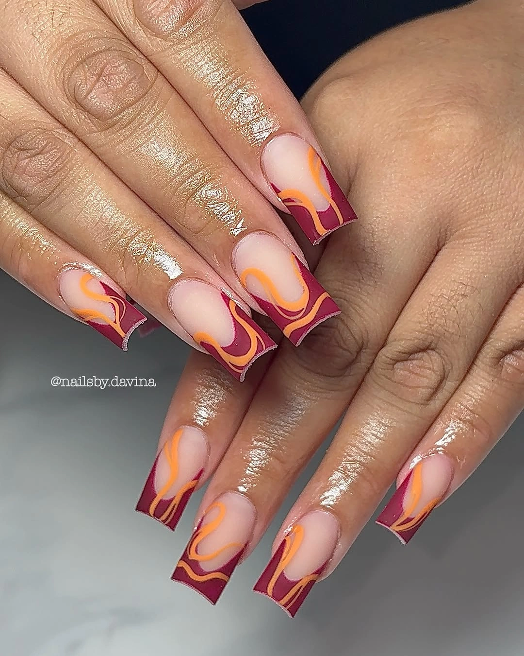 long square nails with pink orange yellow waves and burgundy edge accents