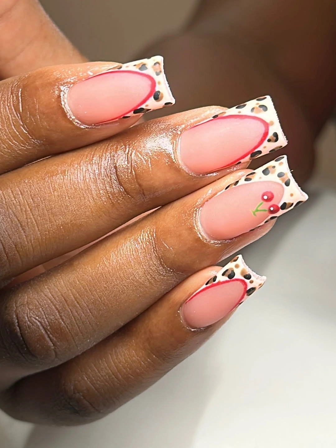 long coral pink square nails with white black dotted tip panels and tiny red accent