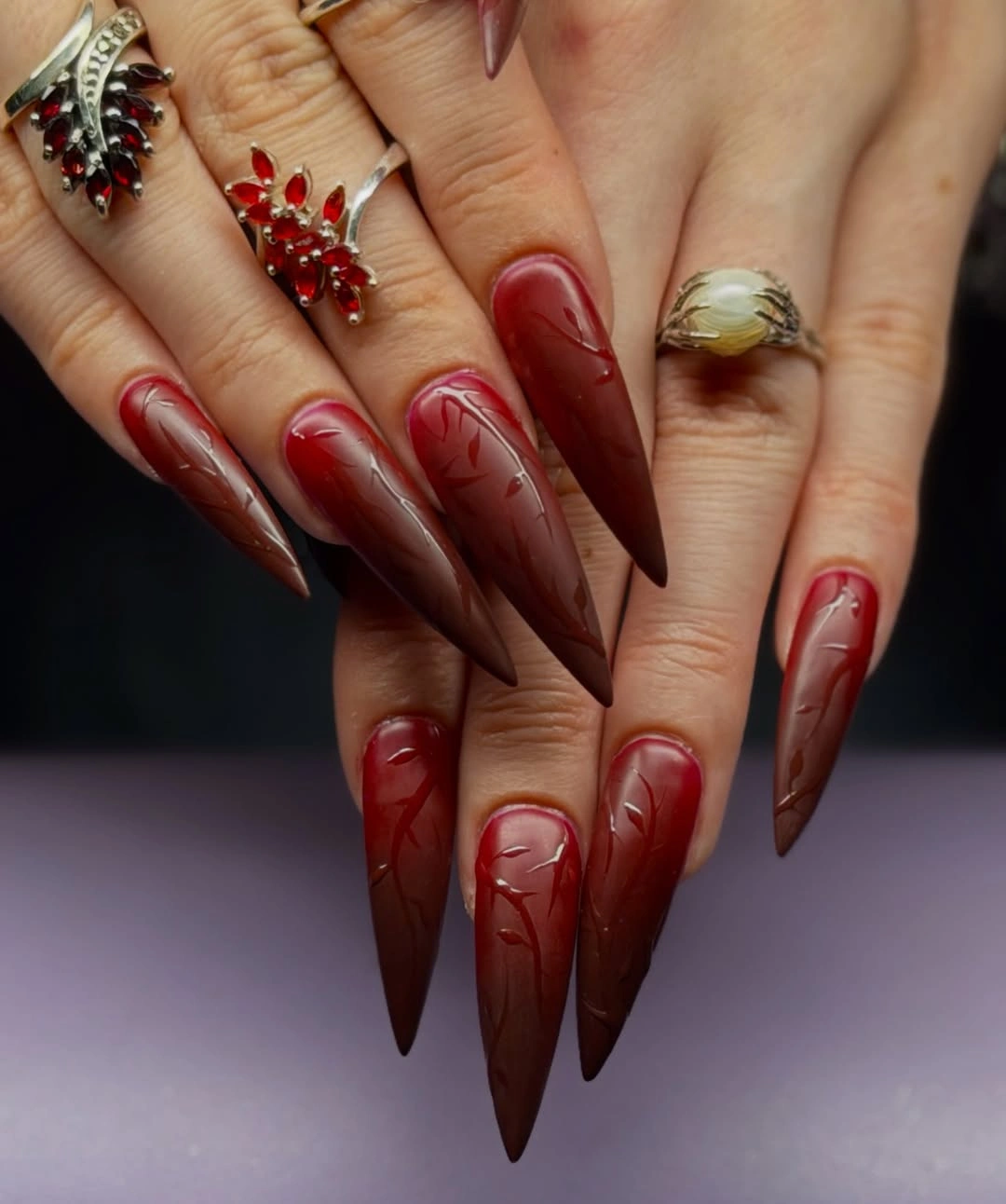 long pointed nails in deep red and brown with curved translucent line accents