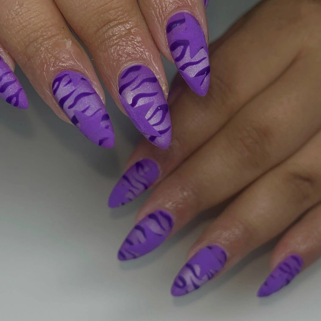 long matte purple pointed nails with bold black zebra-style stripes