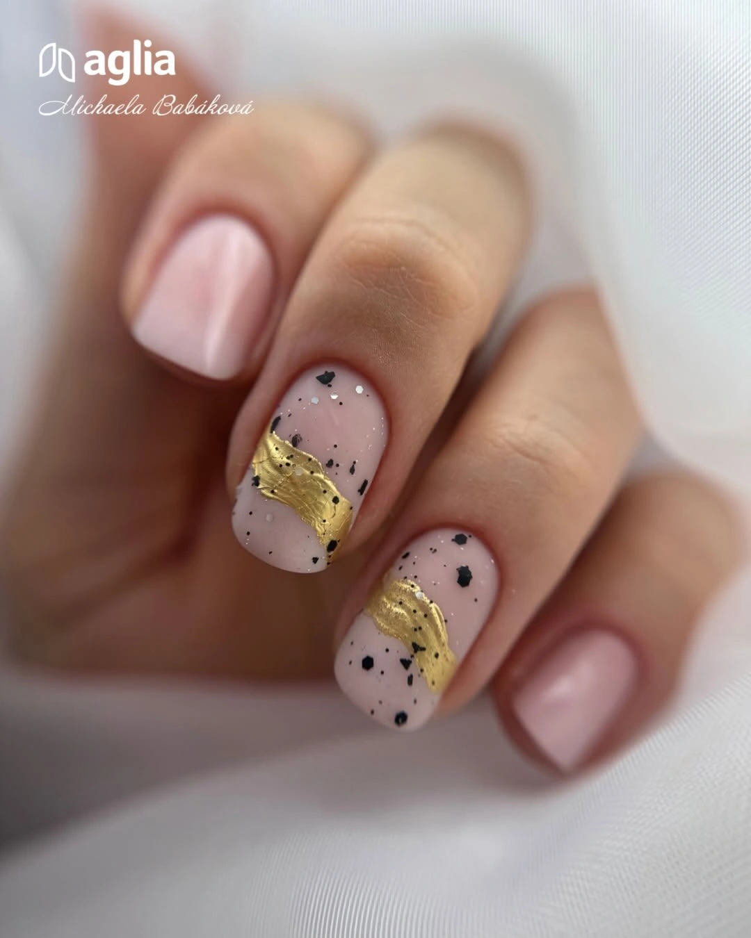 short pale pink nails with black speckles and mustard diagonal accents