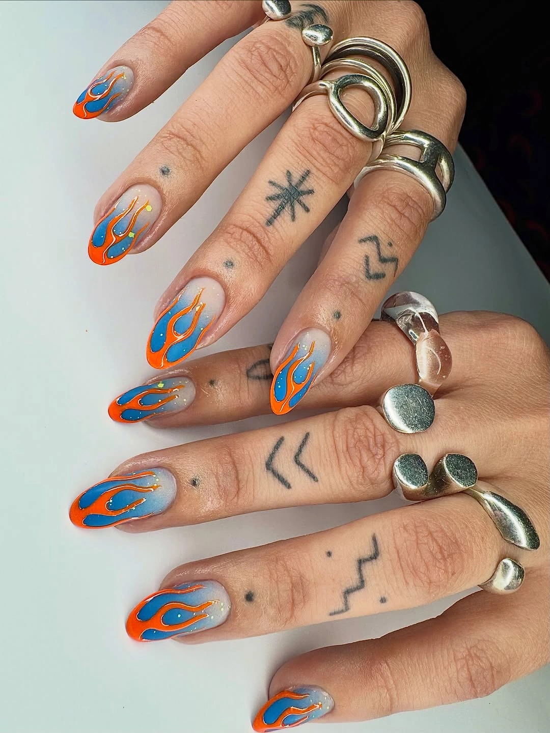 long nude coffin nails with orange and blue flame-like outline accents