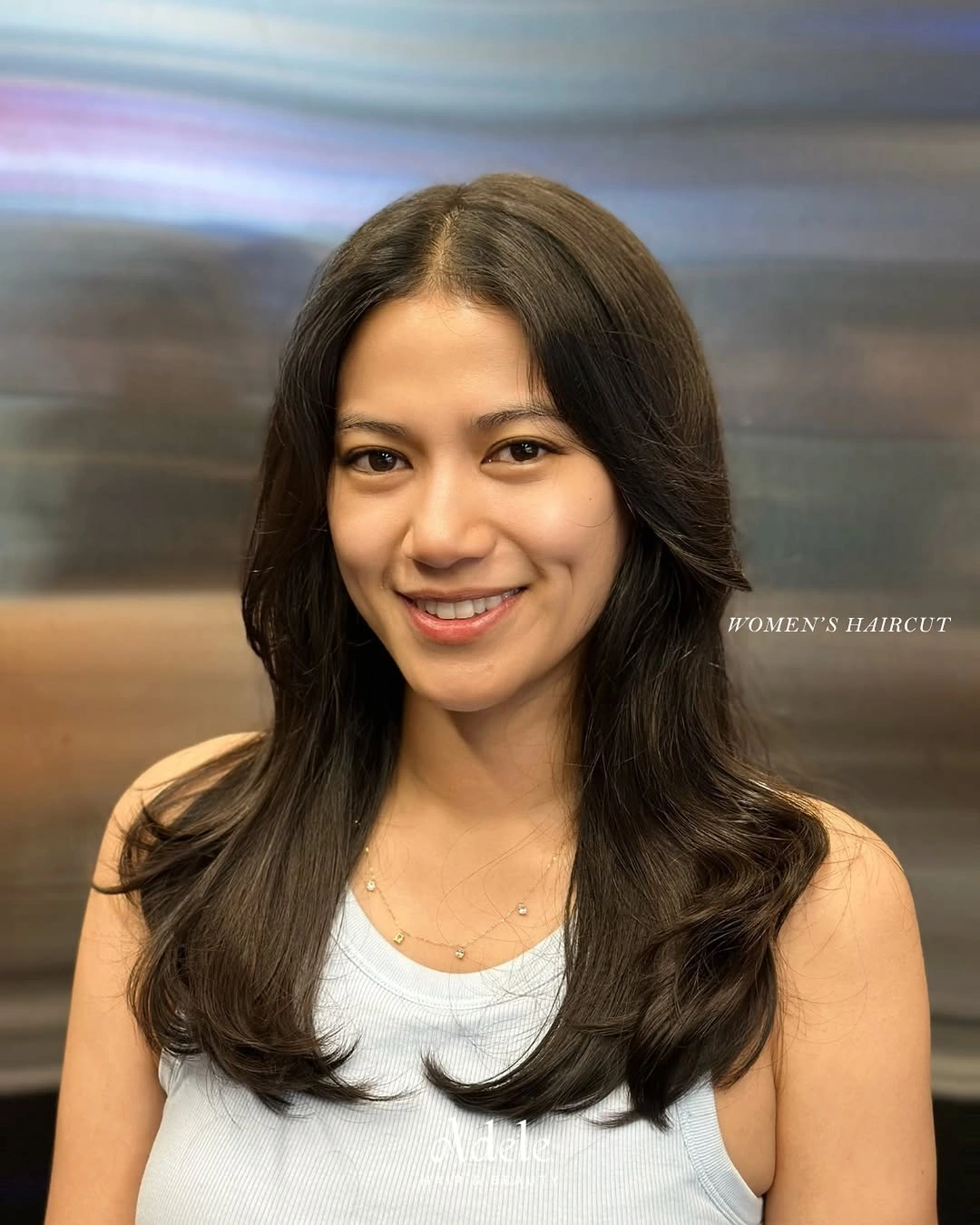Long dark middle-parted hair with soft bends and face-framing layers