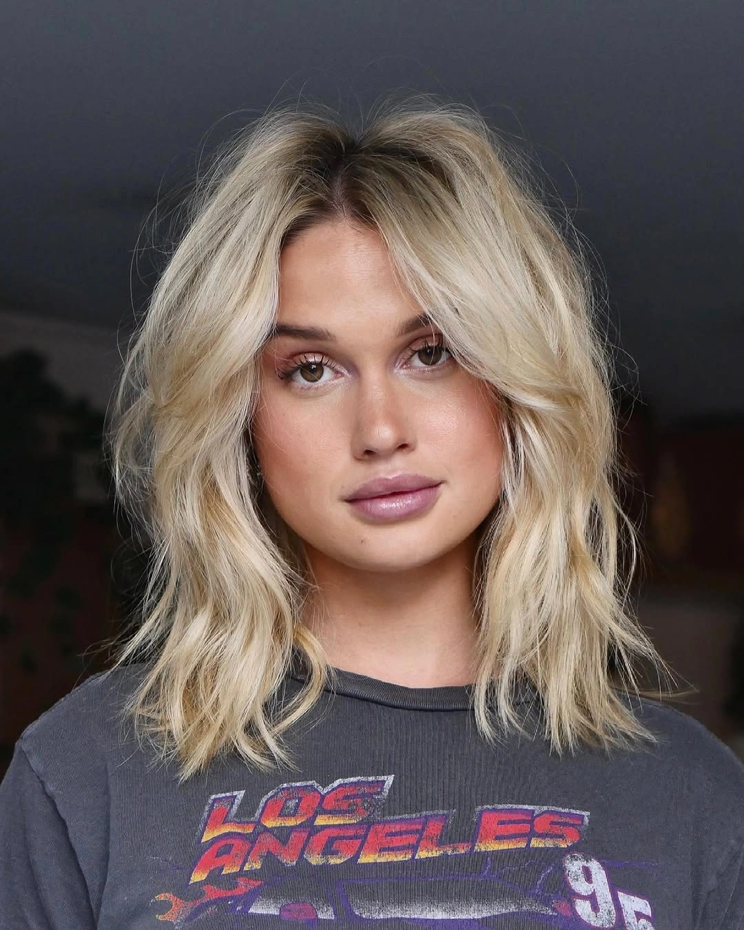 Blonde middle-parted hair with loose waves, curtain pieces, and soft roots