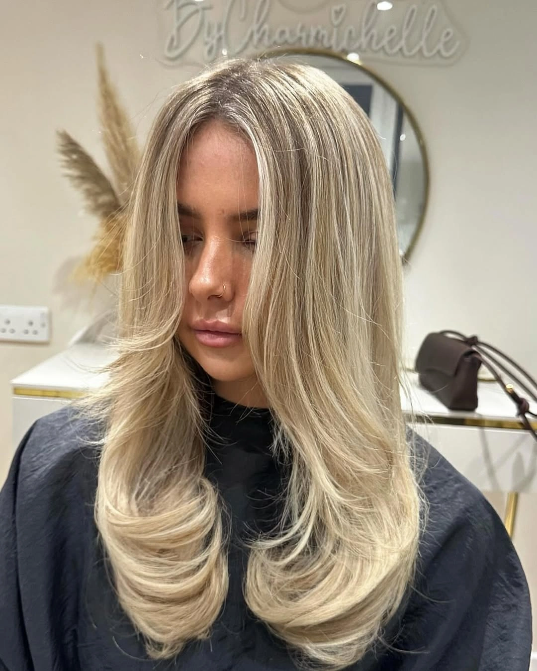 Pale blonde middle-parted hair with feathered layers and sweeping waves