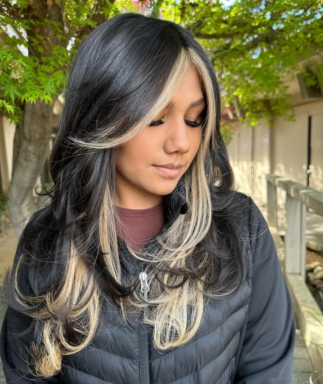 Long dark center-parted waves with pale front streaks and layered curls