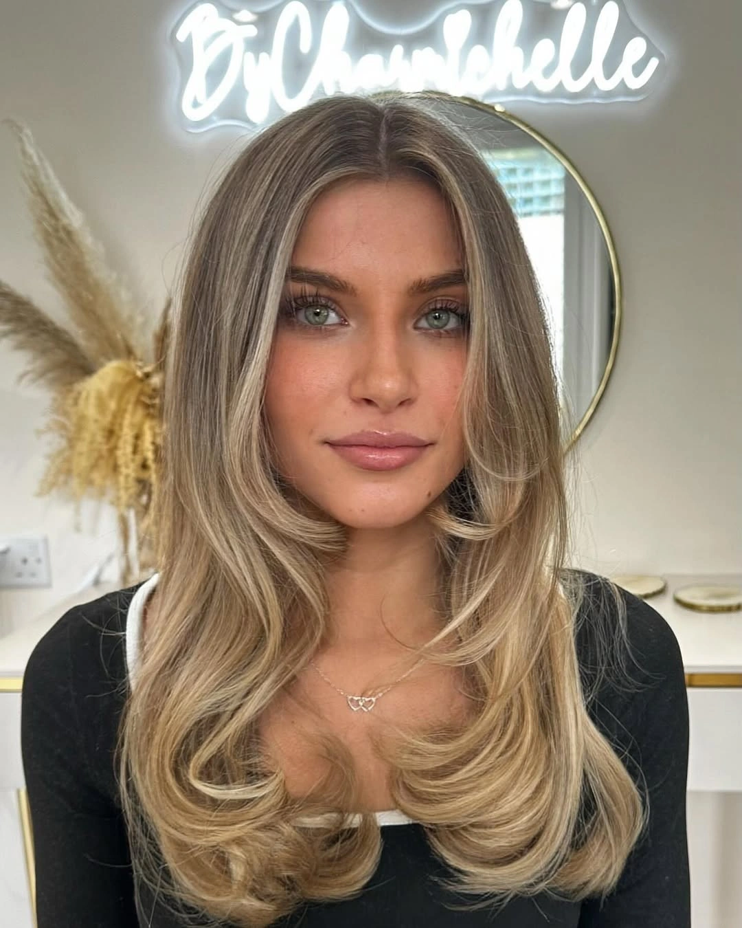 Long blonde center-parted hair with curtain layers and broad waves