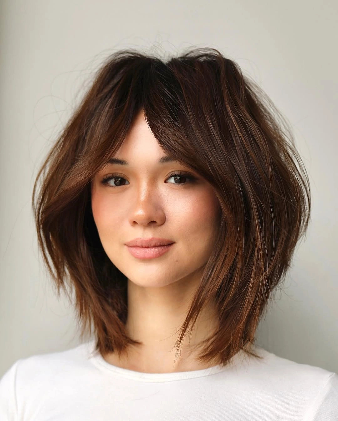 Short brown center-parted bob with airy curtain pieces and turned ends