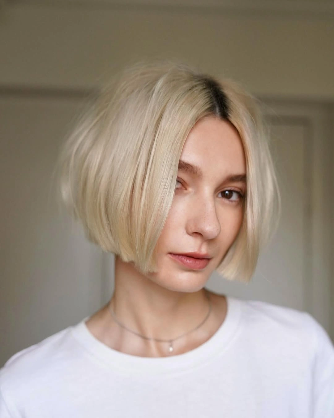 Short pale blonde bob with a centered part and rounded jaw-length shape