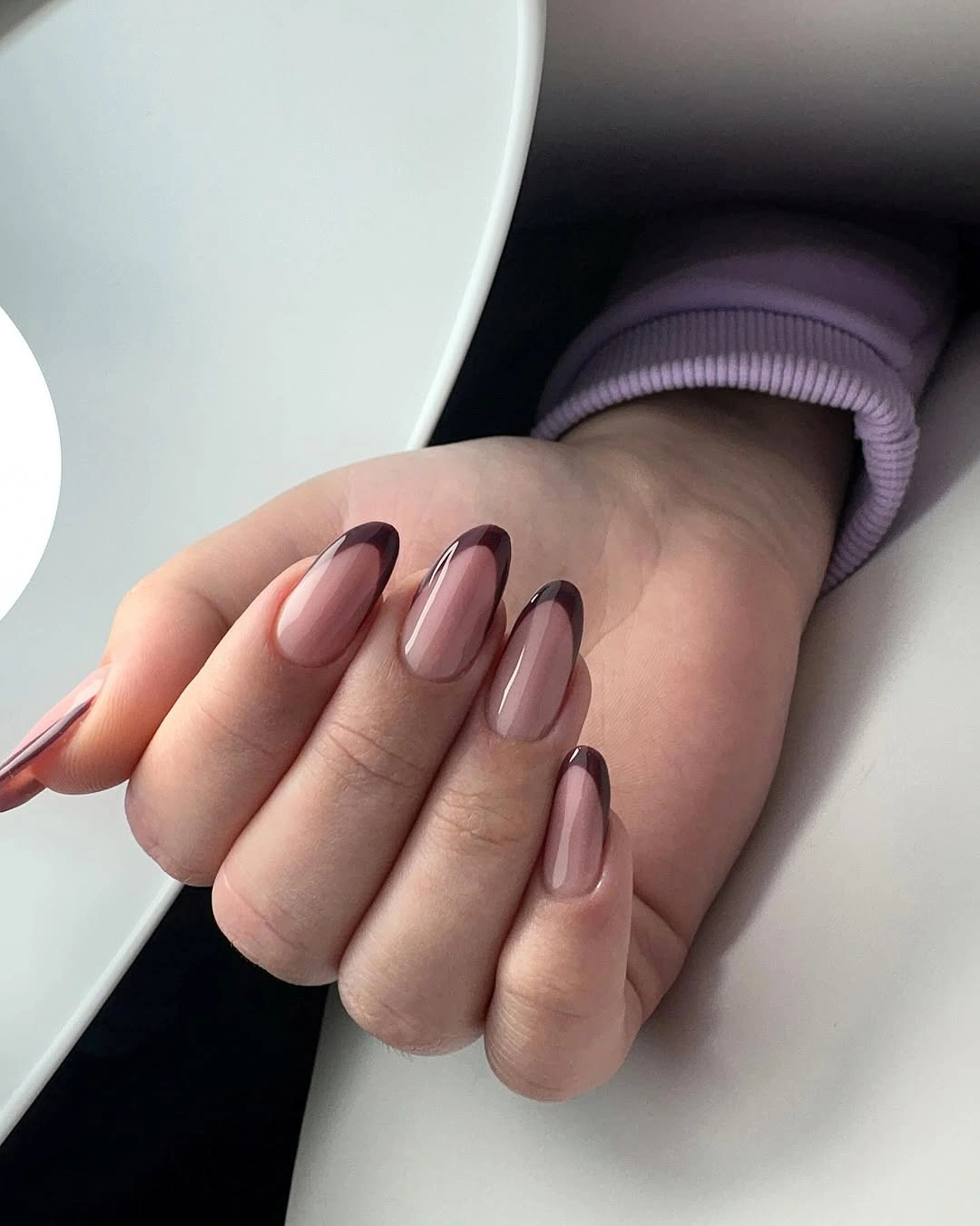 Medium mauve nude almond nails with dark brown contour lines along the edges