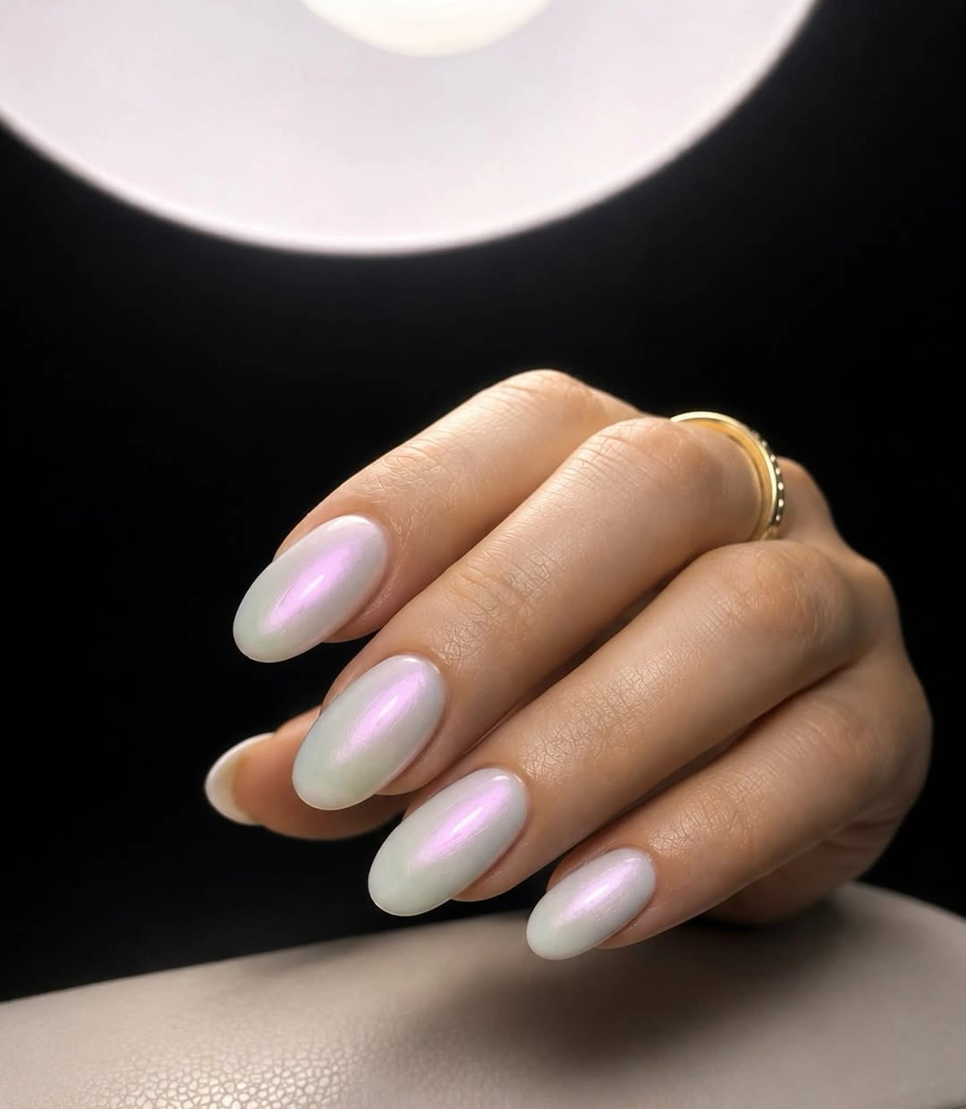 Pale nude almond nails with a soft green-lilac iridescent-looking light shift