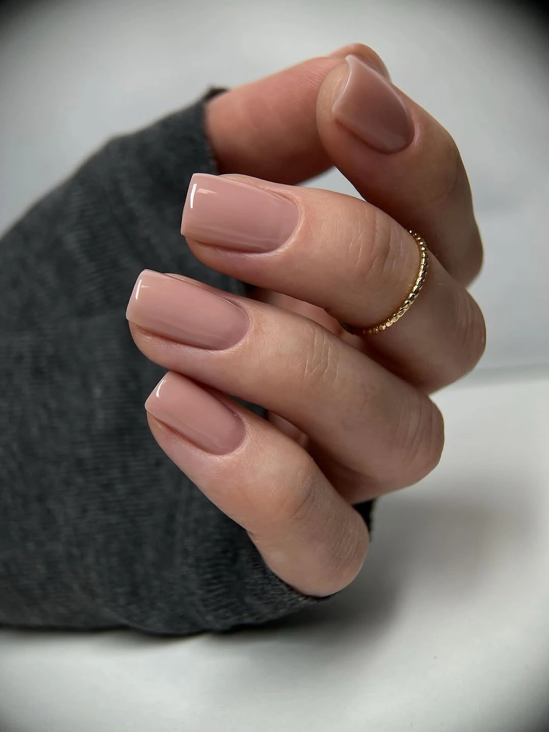 Short square nails in an even glossy warm peachy nude shade