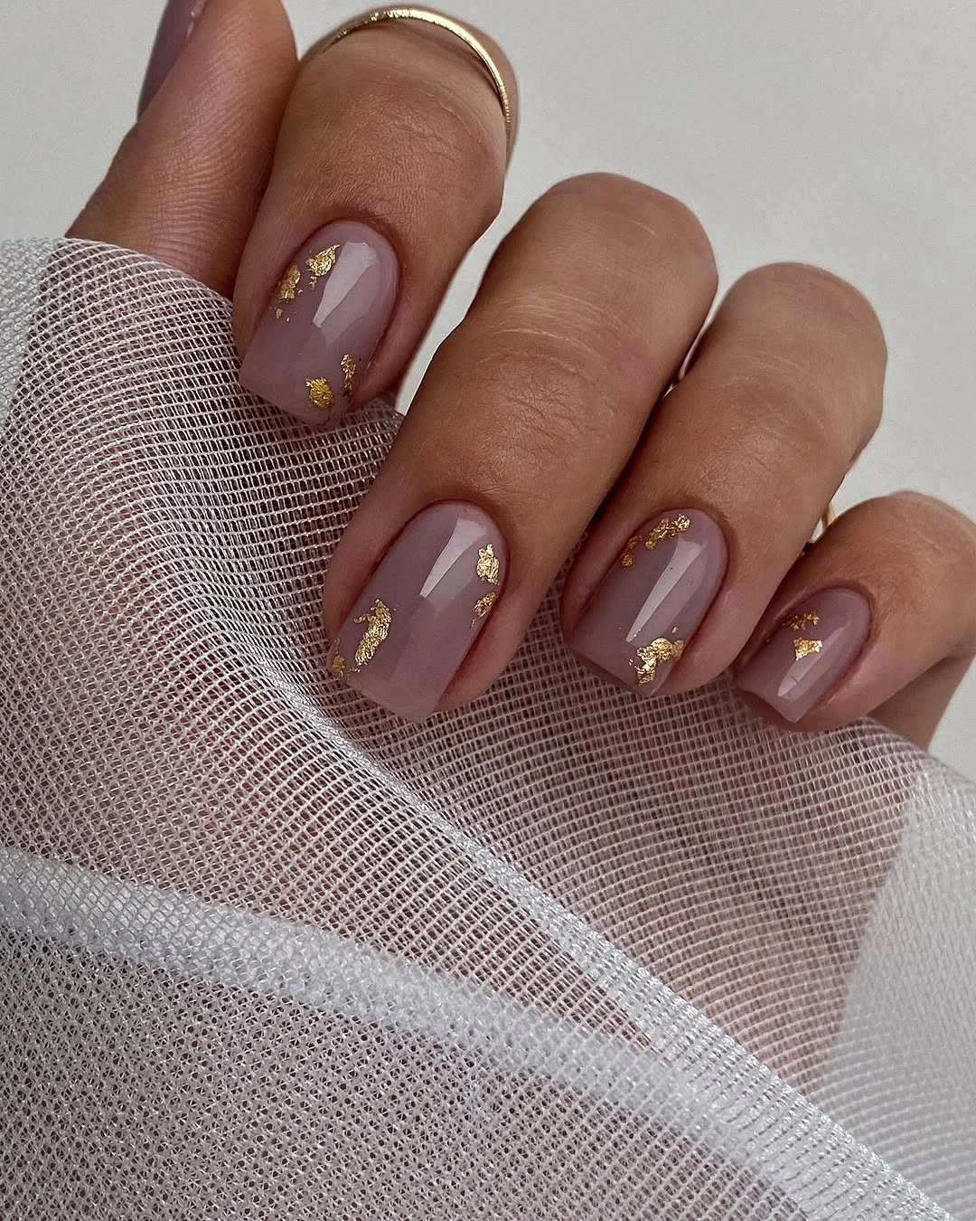 Medium rounded gray-mauve nails with small scattered gold-toned flecks