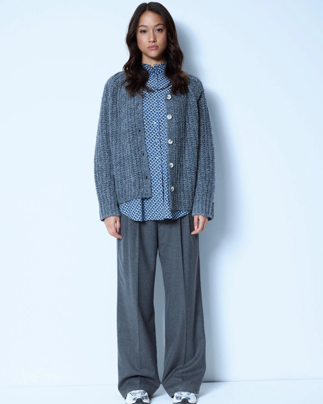 Gray cardigan over patterned blue shirt with loose gray trousers