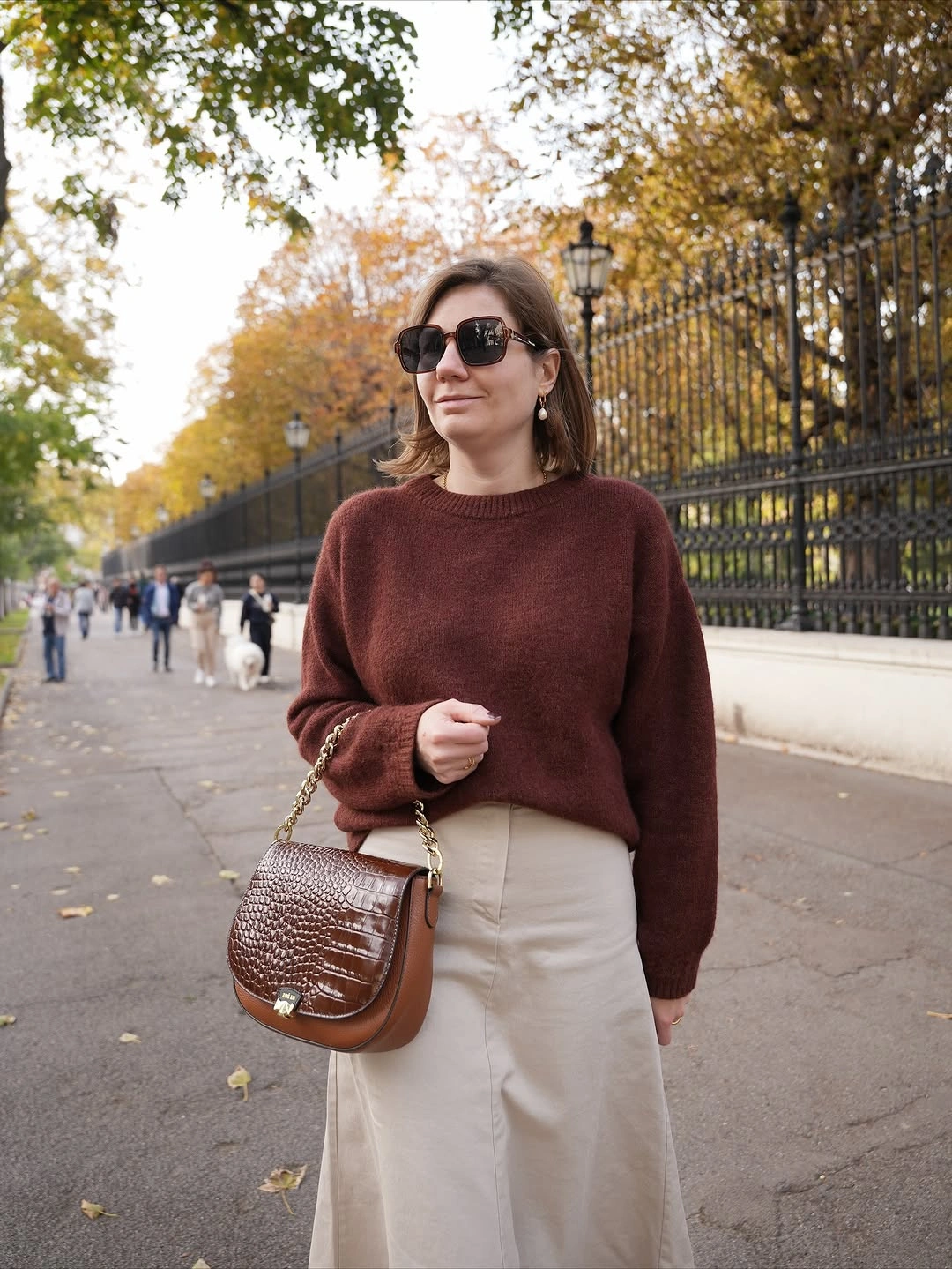 Burgundy sweater with cream wide-leg trousers and brown handbag