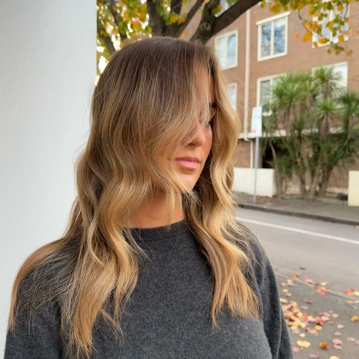 Long honey blonde waves with darker beige root area