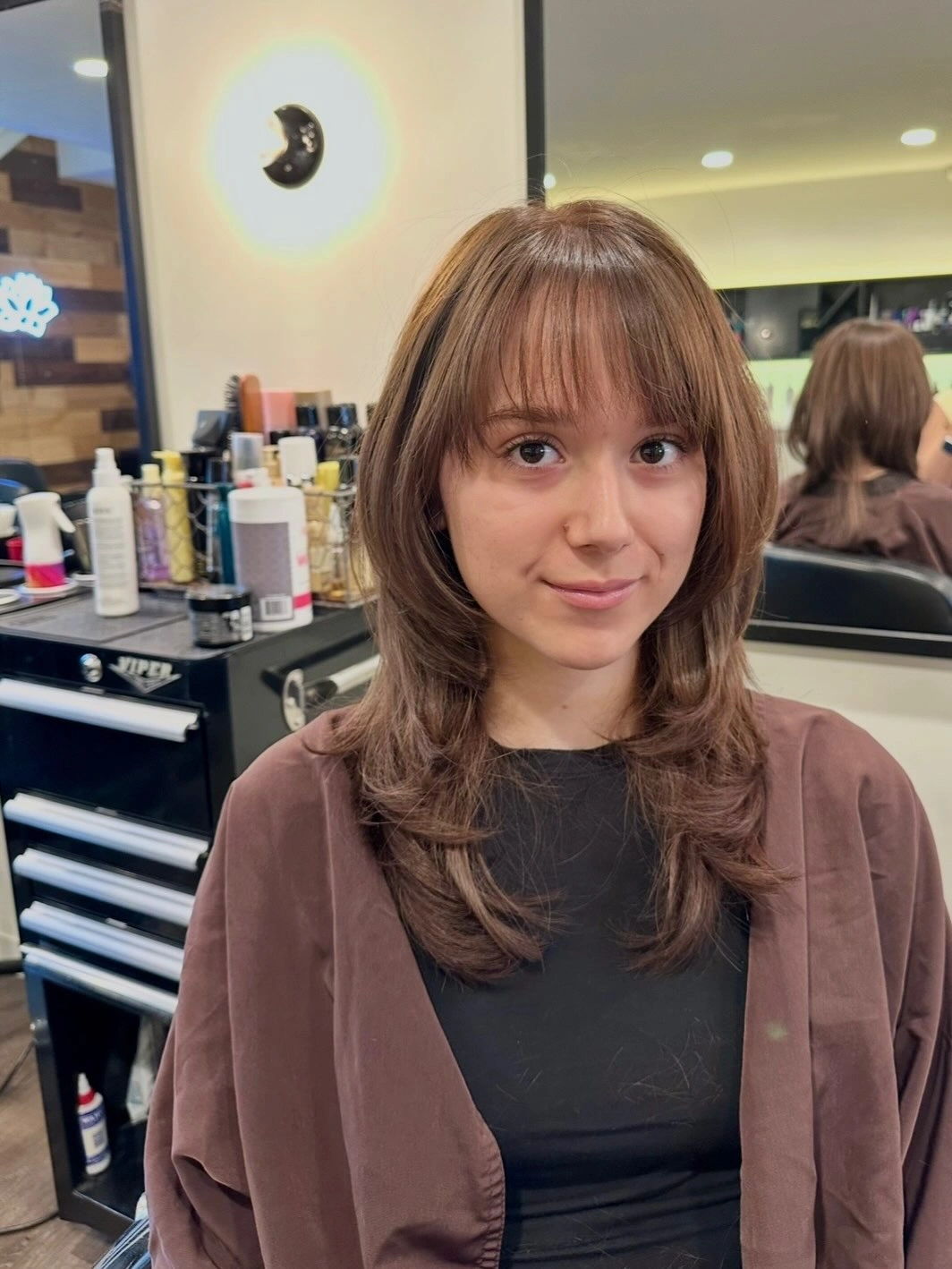 Medium chestnut layered hair with wispy fringe and turned ends