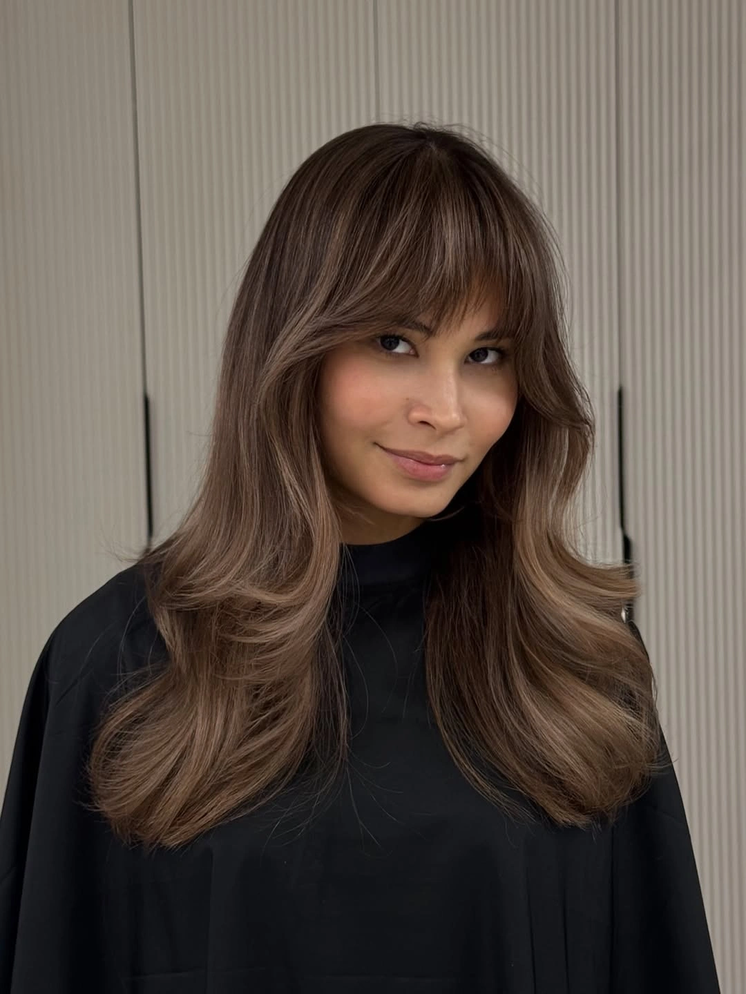 Long taupe brown hair with full fringe and bouncy layers