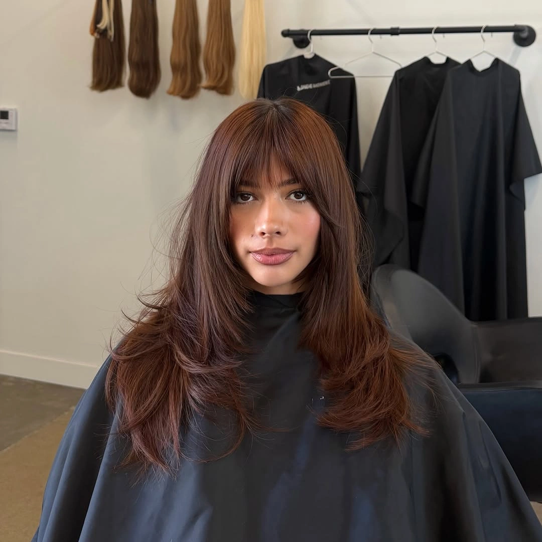 Long dark hair with full wispy fringe and soft layers
