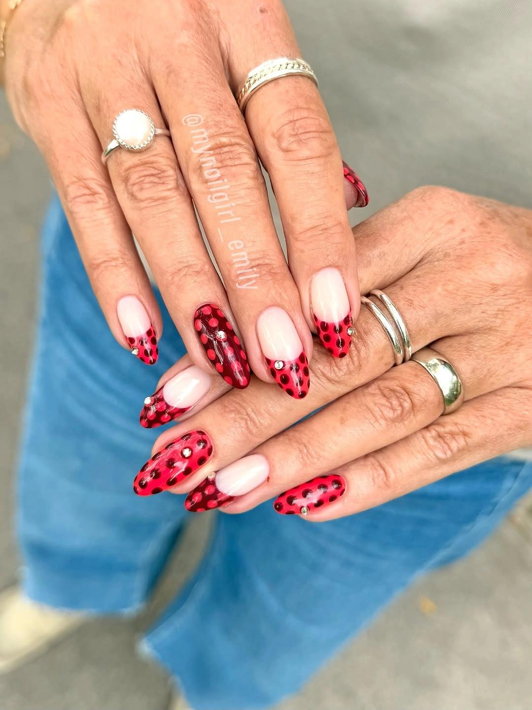 Creamy nude almond nails with small red and black dot accents