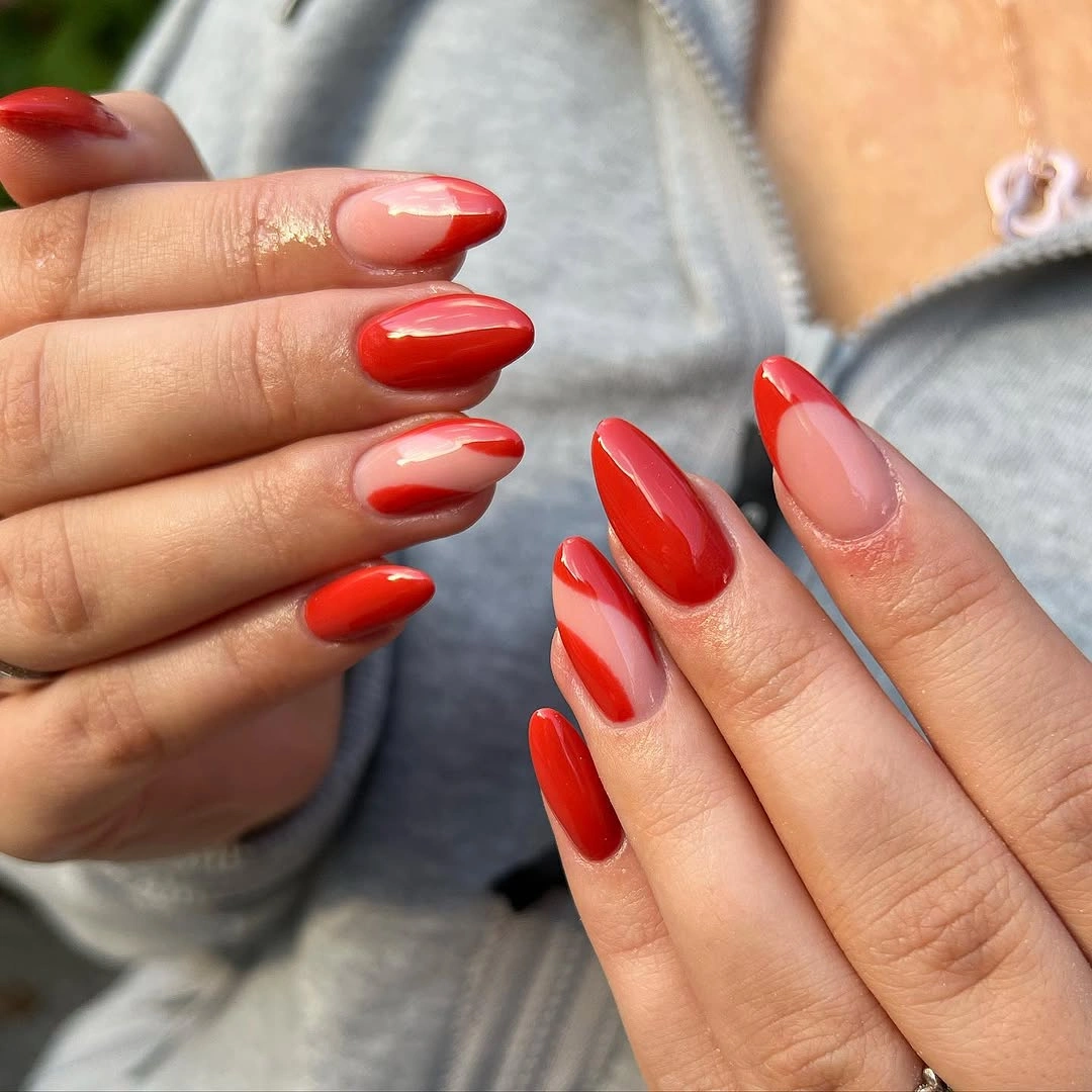 Red nude almond nails with sweeping white and red waves