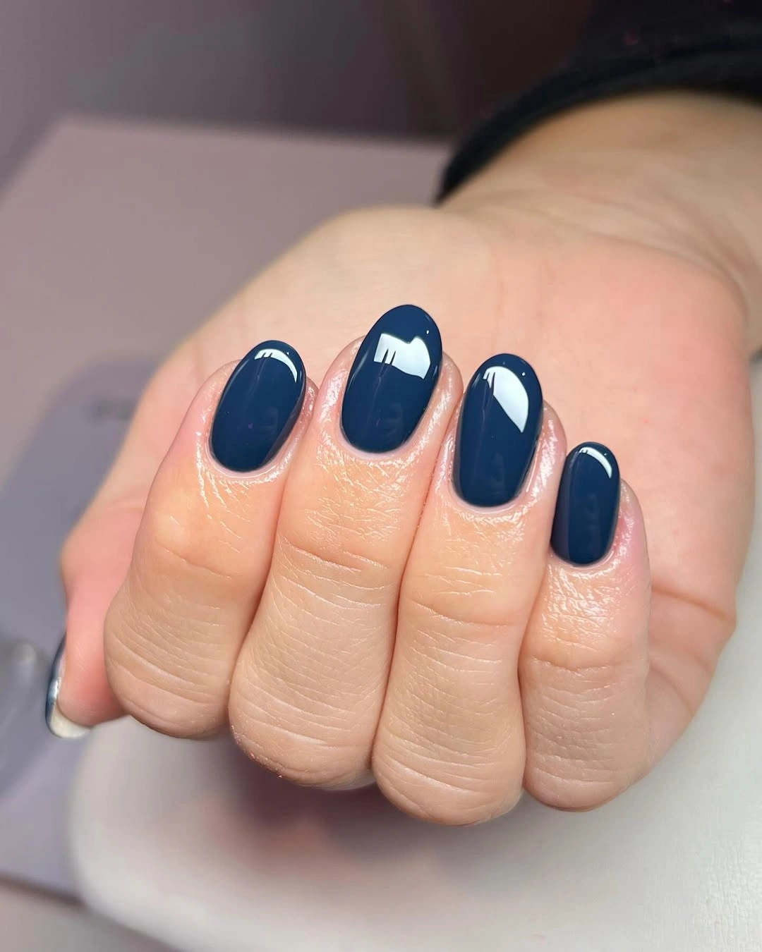 Short rounded deep navy nails with pale curved details