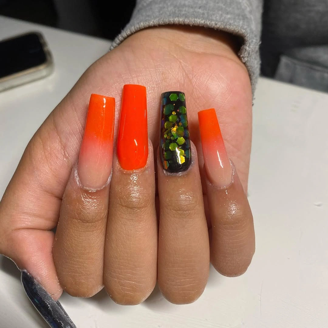 Long orange coffin nails with dark botanical detail