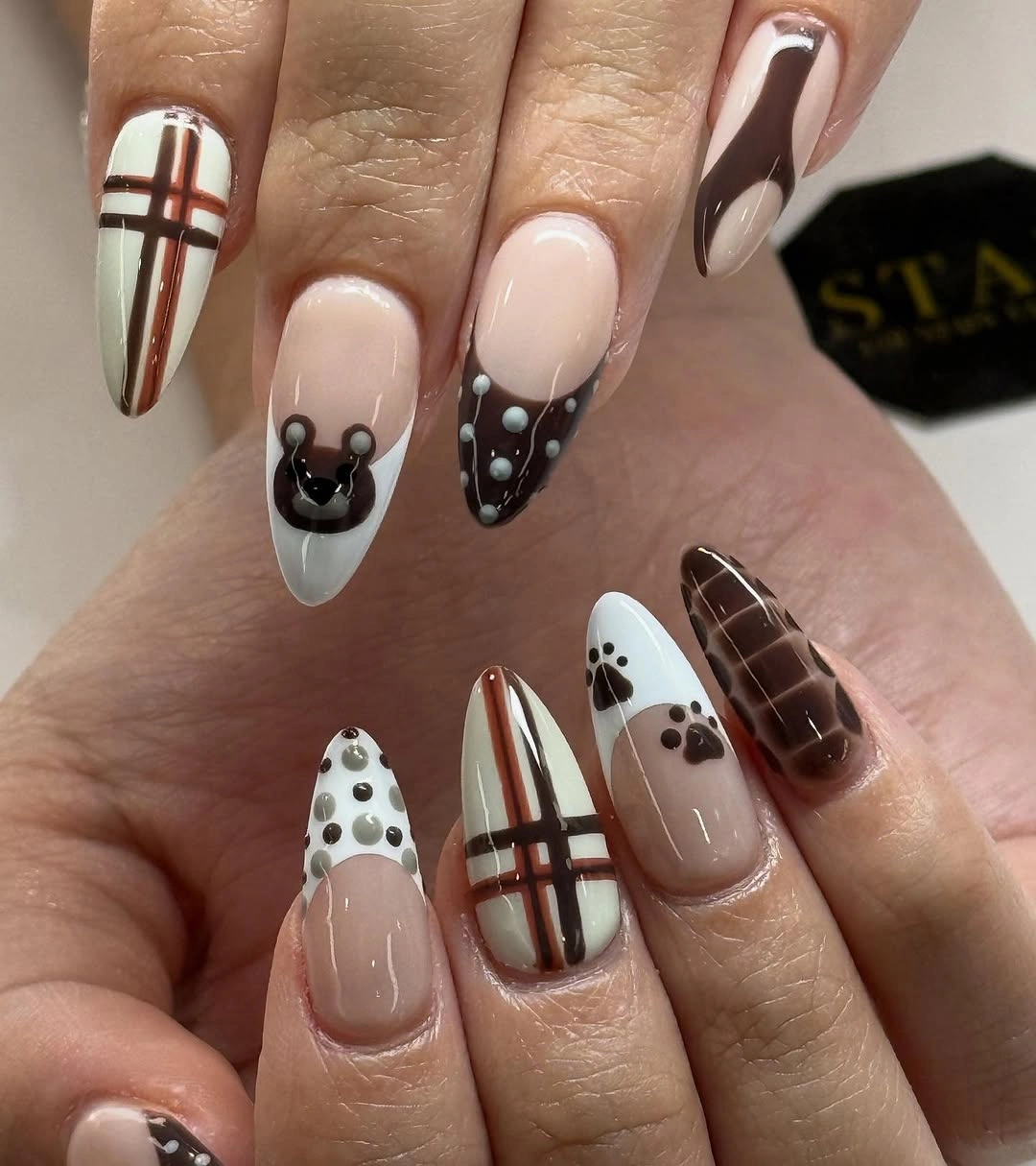 Warm nude almond nails with brown checks and dot accents