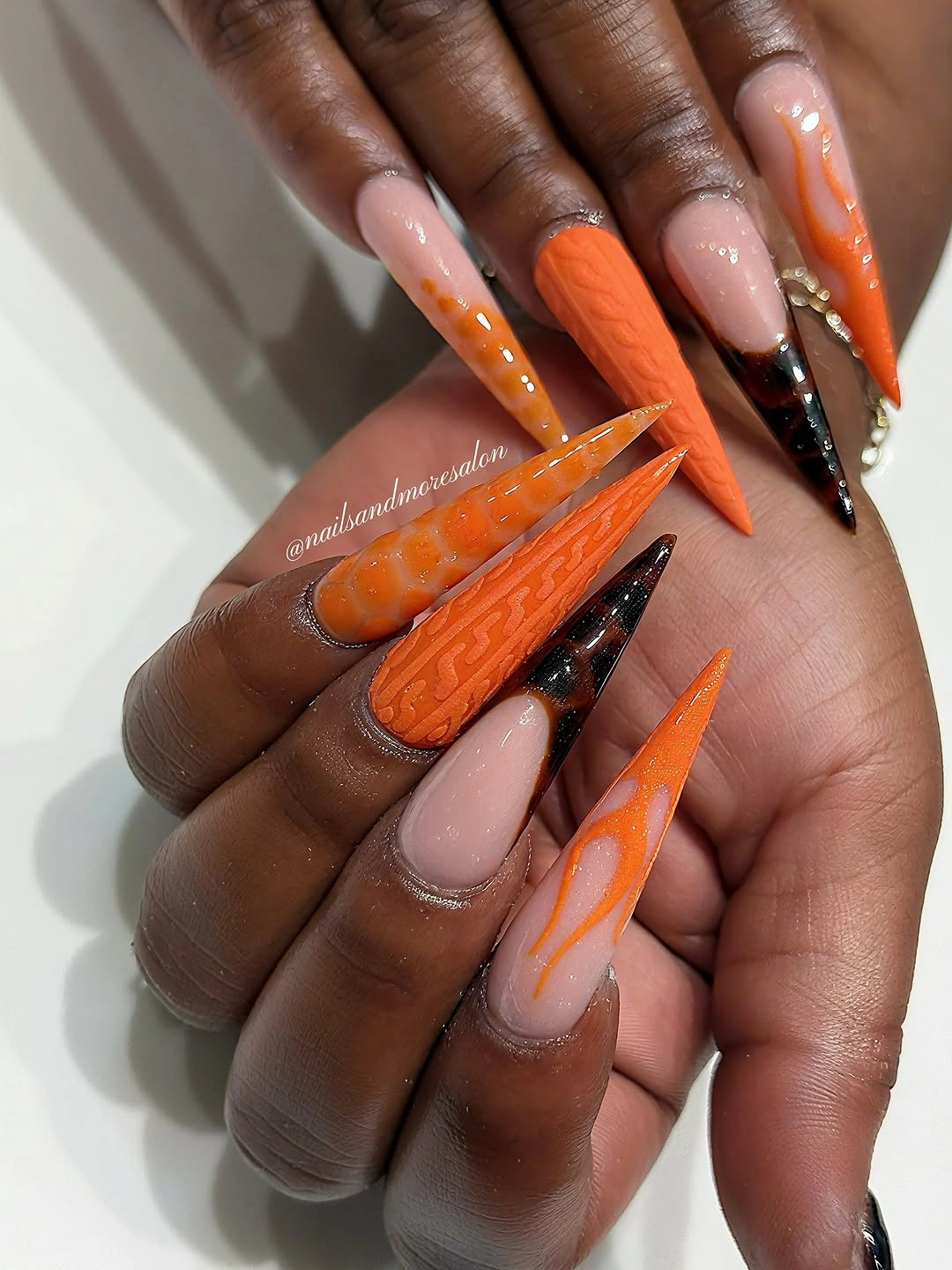 Long orange nude stiletto nails with black flame details