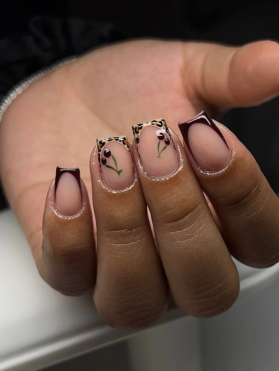 Short sheer nails with fine black curves and green accents