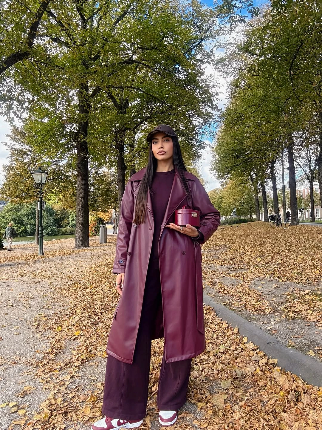 Long burgundy coat matching trousers white sneakers and black cap