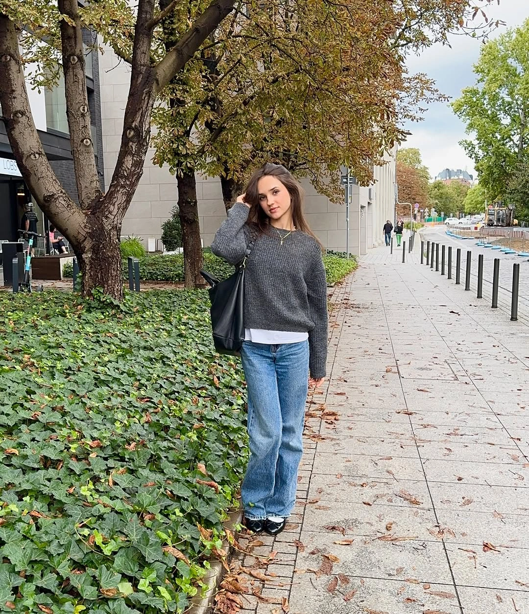 Charcoal sweater white undershirt wide blue jeans and black bag