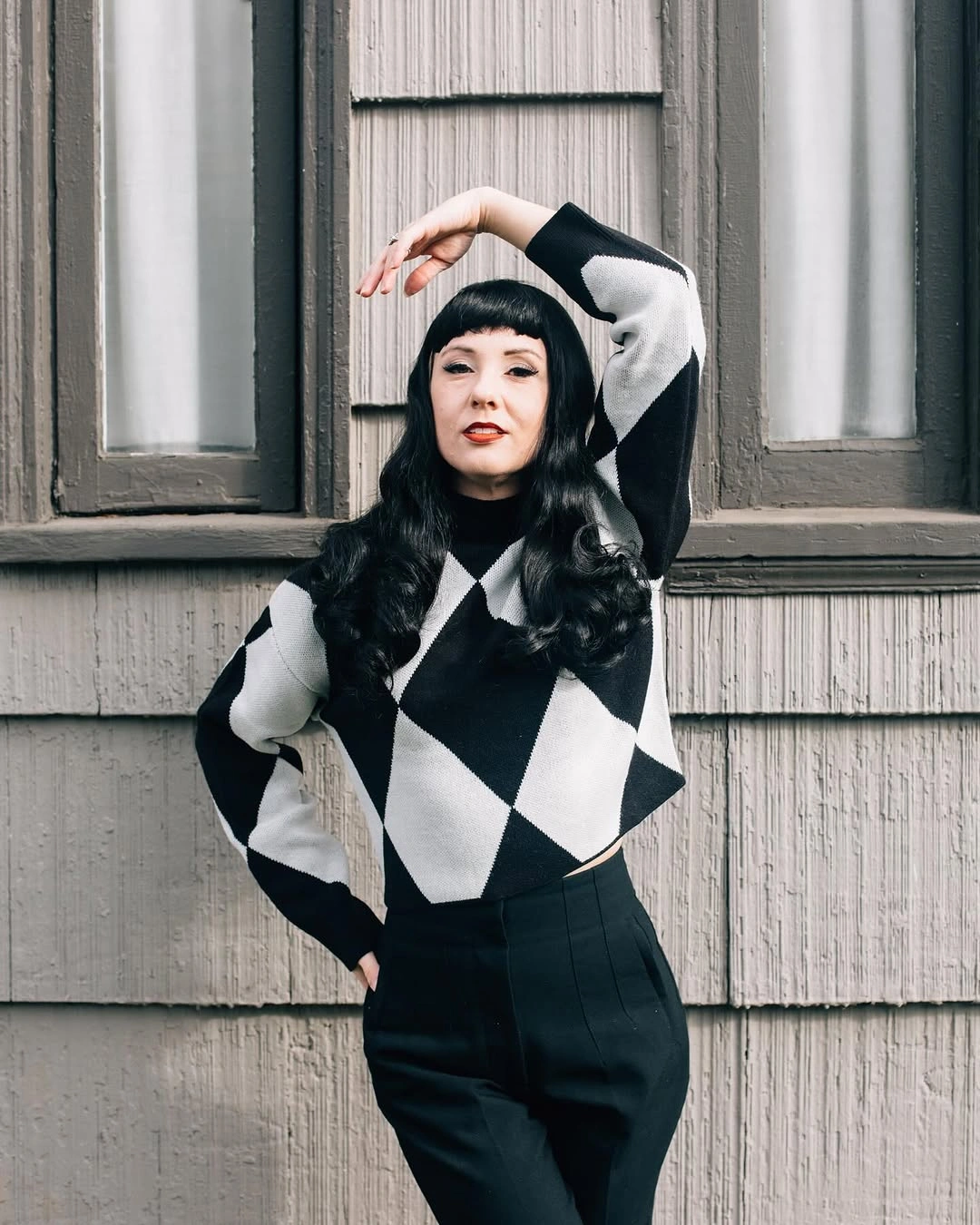 Black and cream checkerboard sweater with black trousers and cap