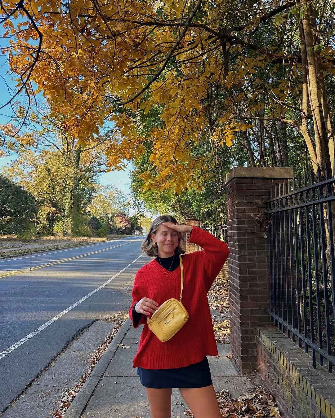 Red sweater black mini skirt knee boots and yellow bag