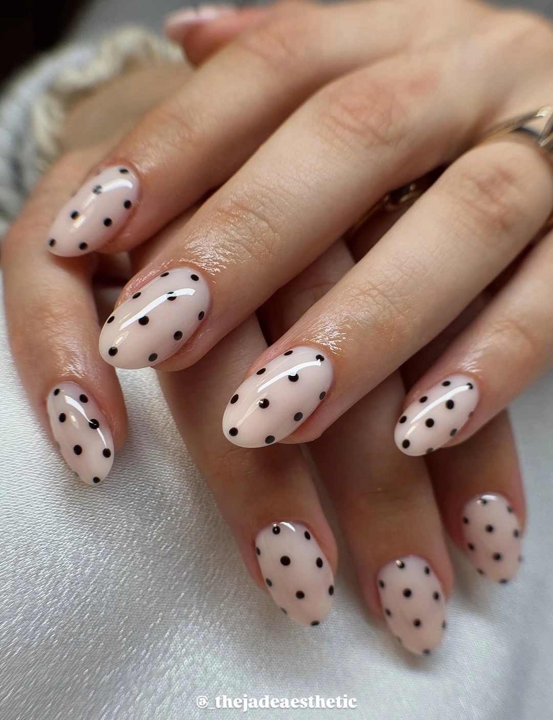 medium cream almond nails with sparse scattered black polka dots