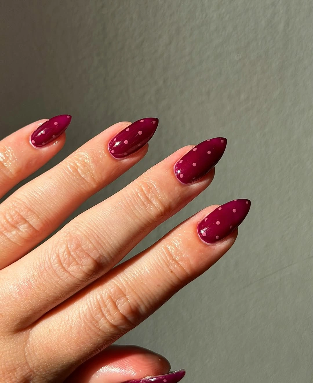 deep maroon almond nails with tiny white microdots near the upper area