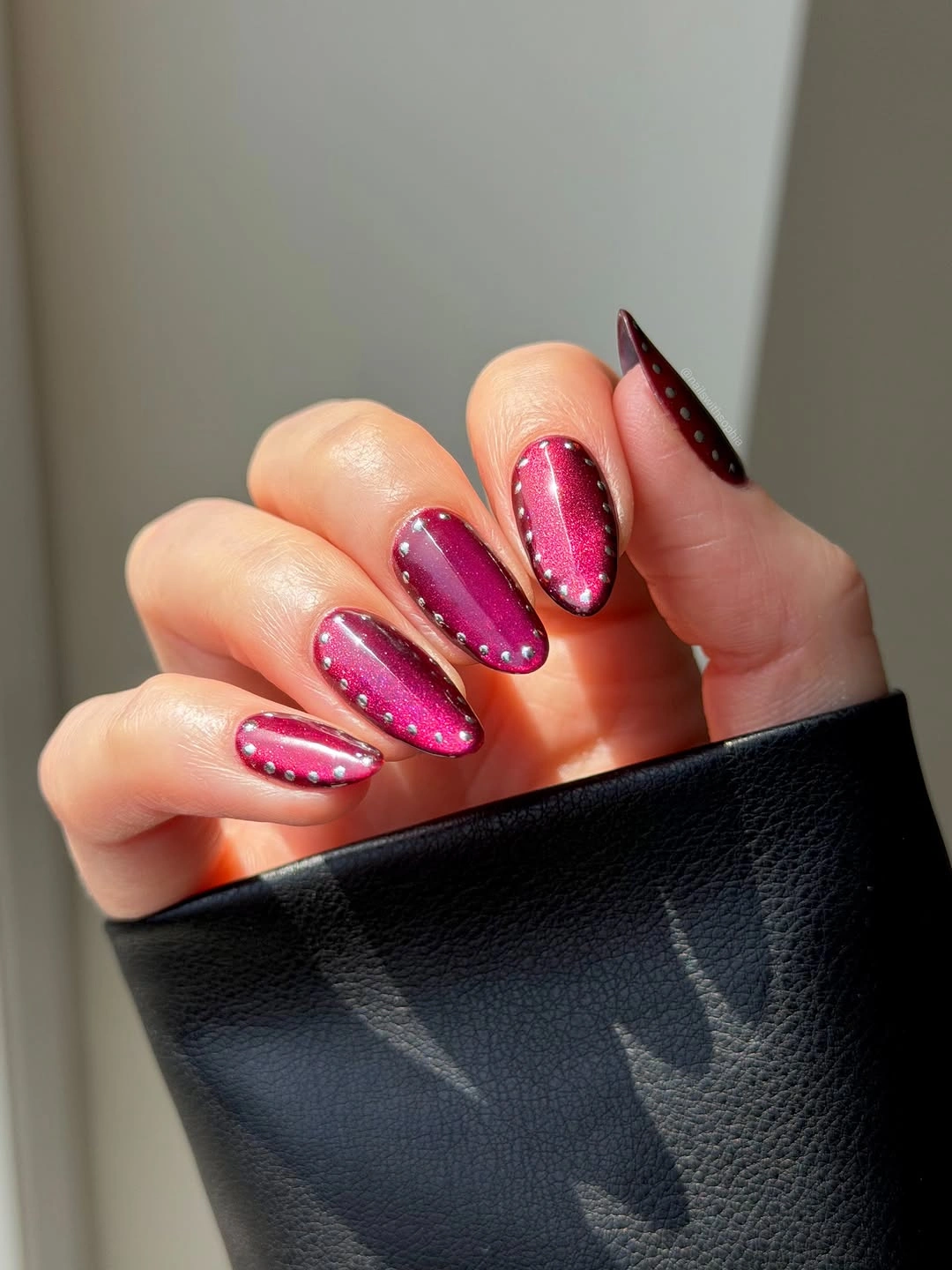 long hot pink almond nails with white dotted sections and sharp dark tip accents