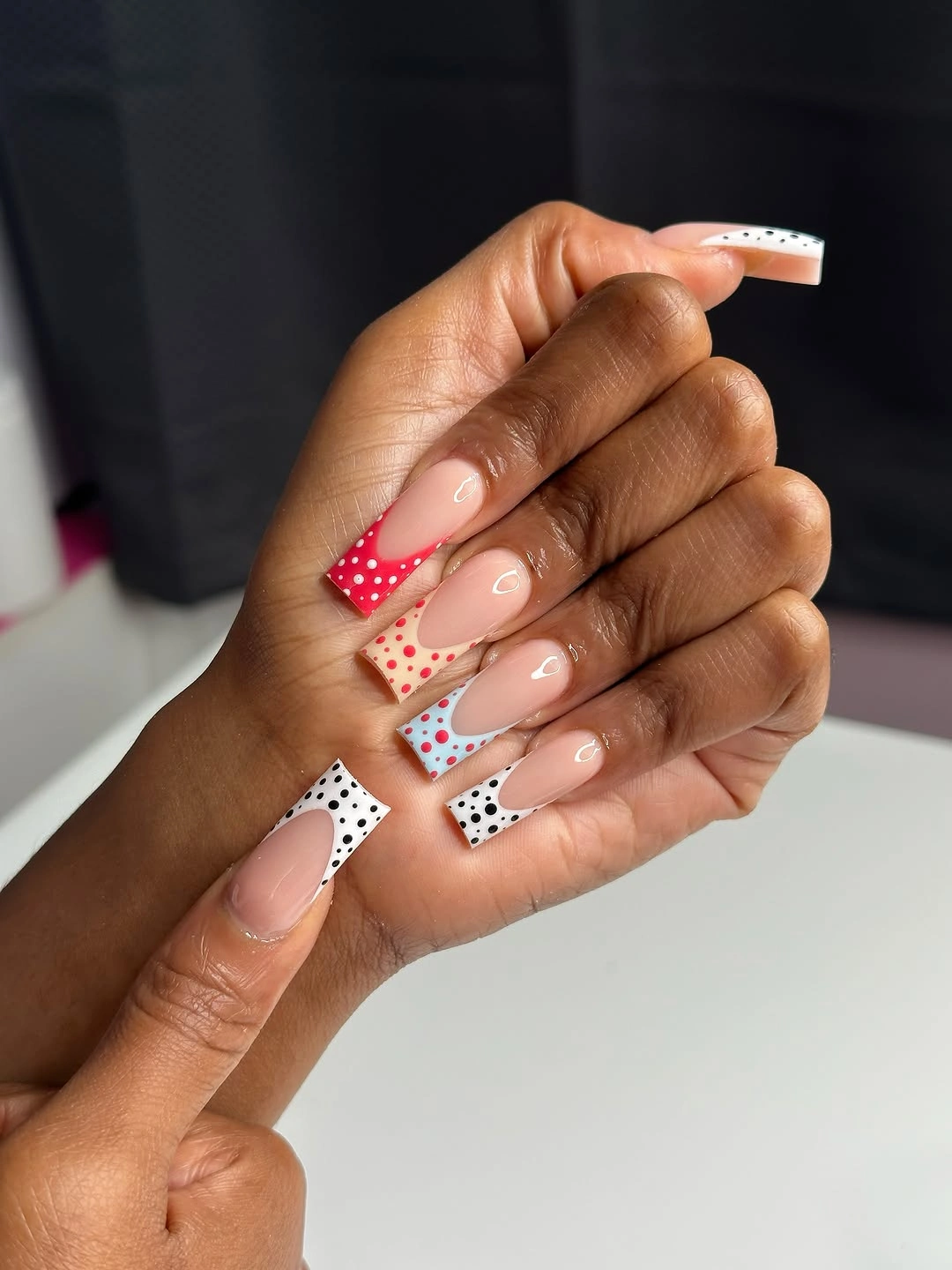 long nude square nails with white black dotted panels and red dotted accents