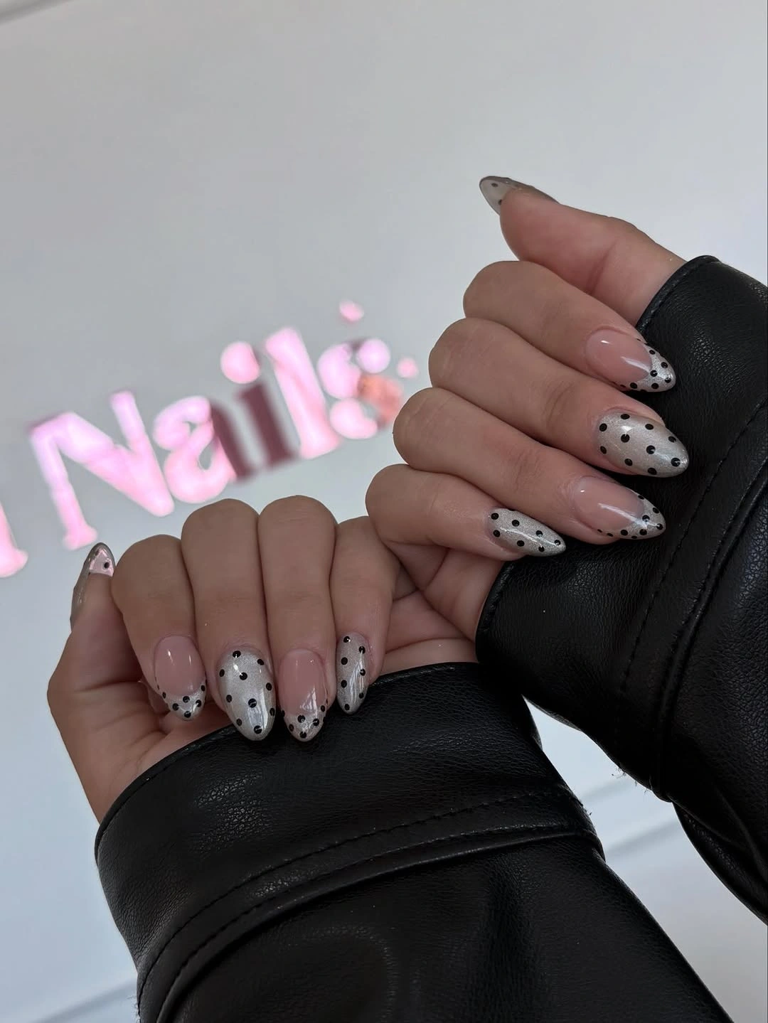 medium cream almond nails with black polka dots concentrated toward the tips