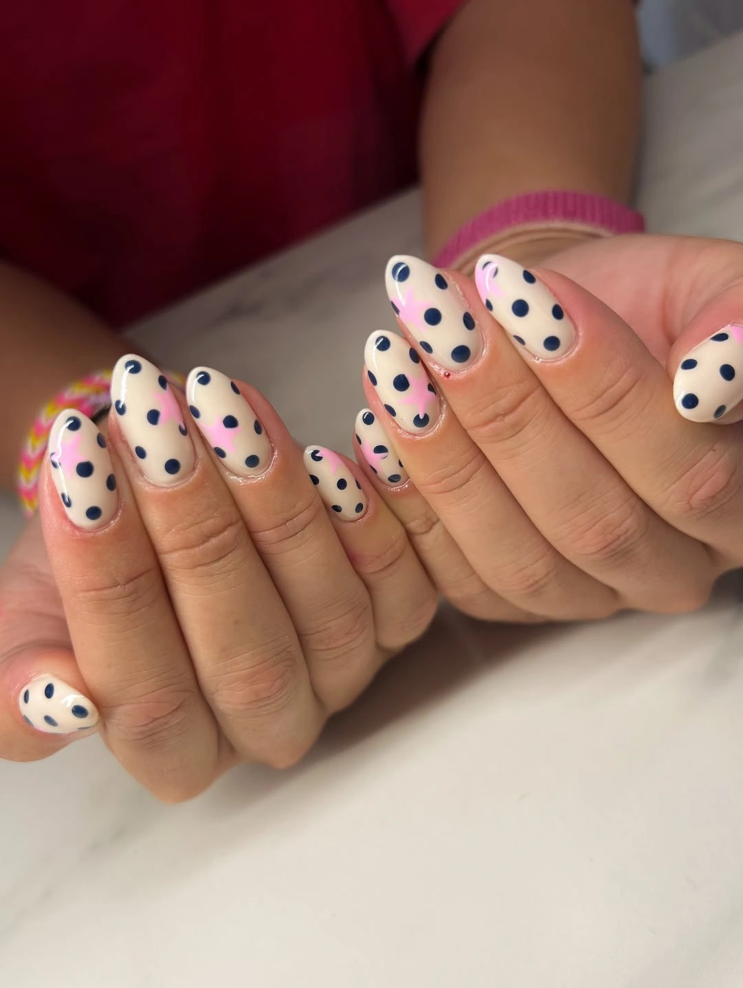 medium cream almond nails with spaced red navy pink and yellow polka dots