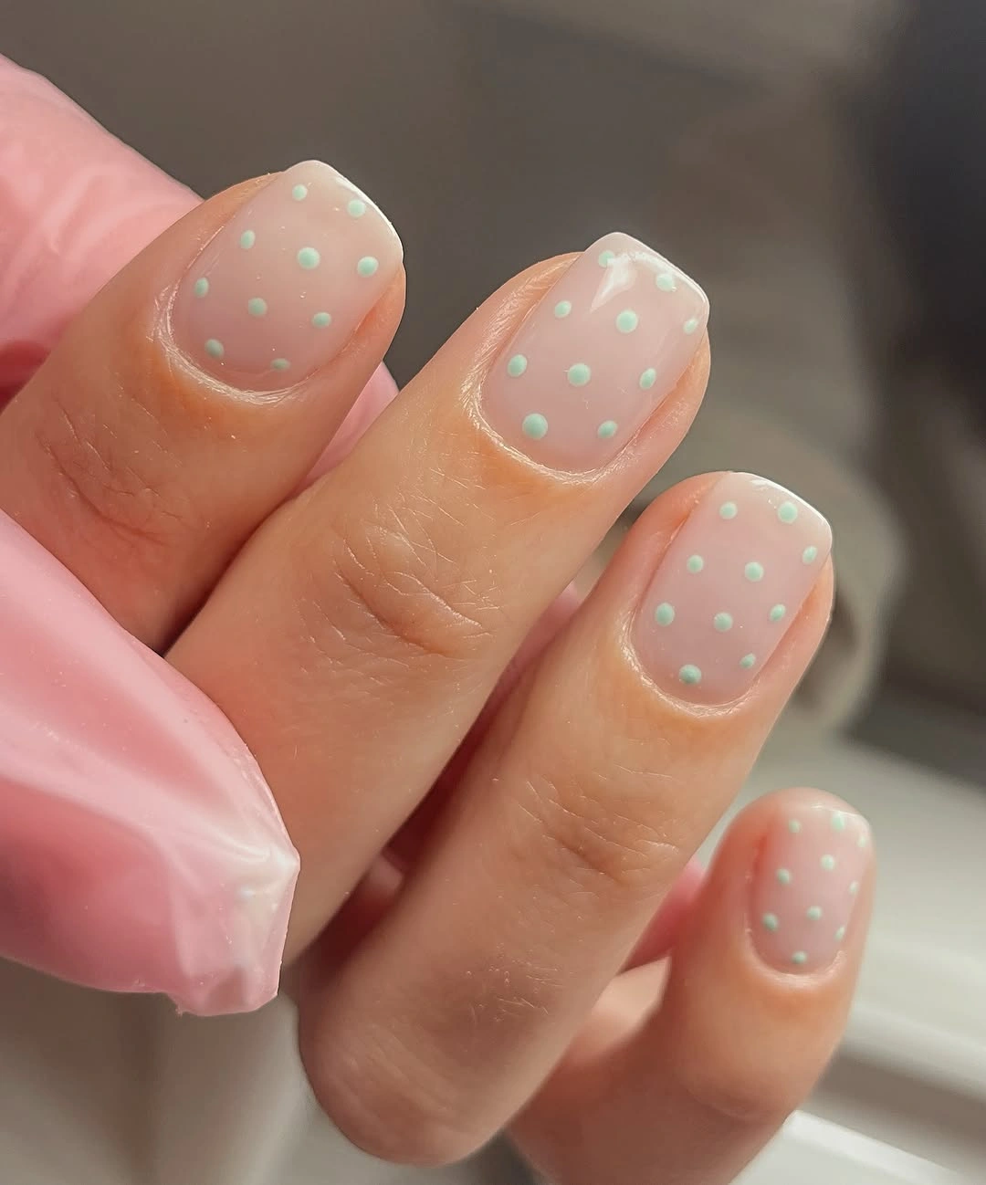 short nude rounded square nails with evenly spaced tiny mint green dots