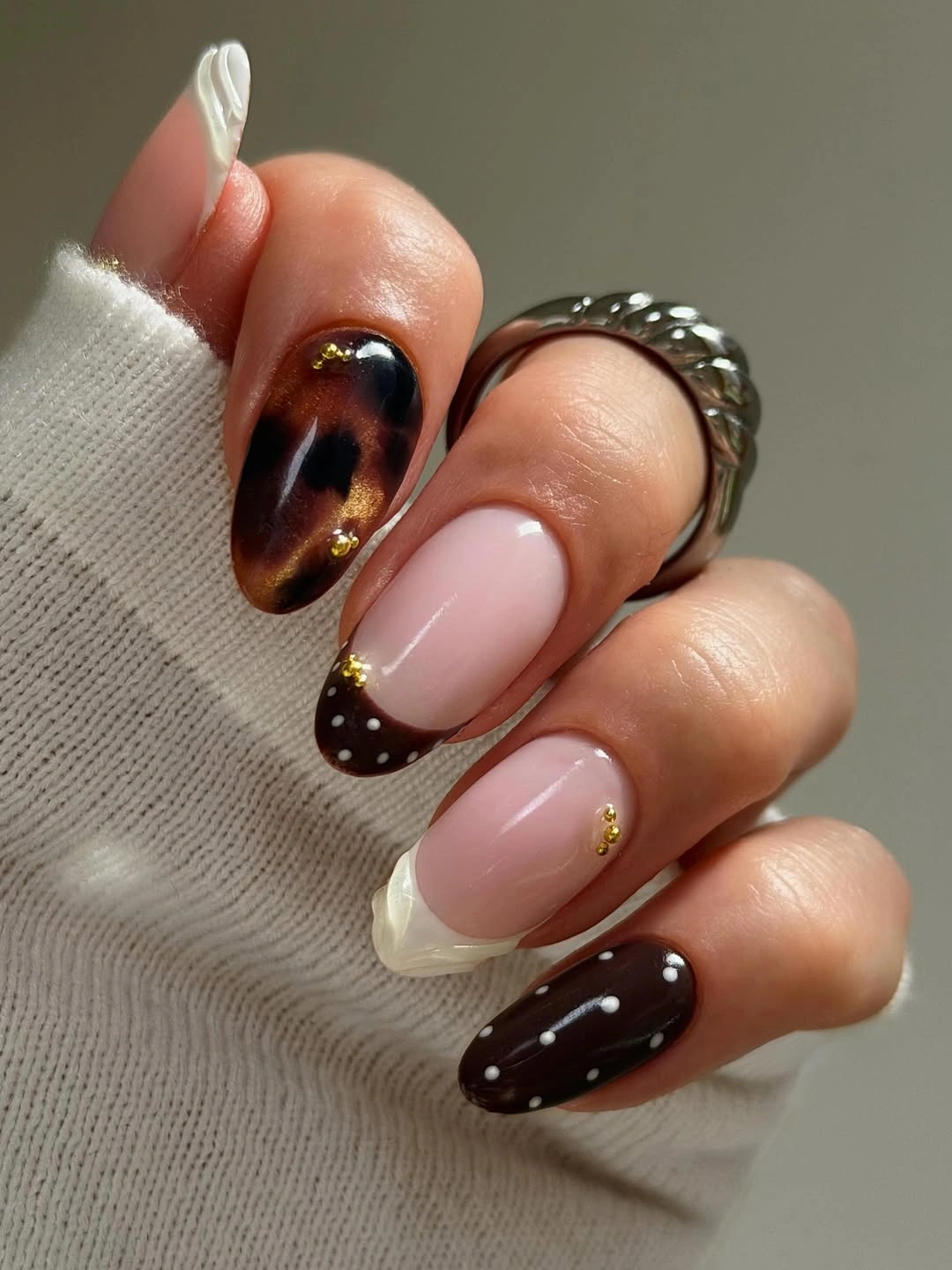 short pale pink almond nails with tortoiseshell sections white accent and tiny dots