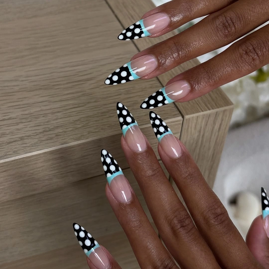 long pale pink pointed nails with black and white polka dot French tips